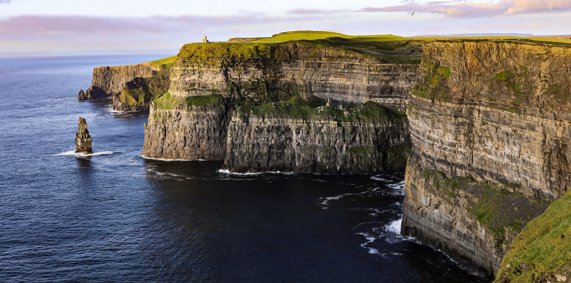 Breath taking view of the Cliffs of Moher in Ireland taken by Myk Klemme. The cliffs are a steep vertical drop with clear layers visible in the exposed rock showing a landscape formed over a long time